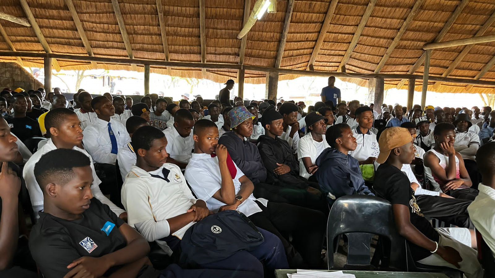 Learners in a large workshop under a thatched hall